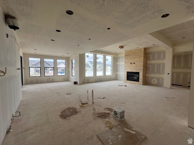 unfurnished living room with plenty of natural light and a stone fireplace
