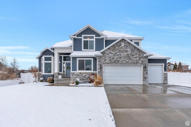 craftsman inspired home with stone siding, an attached garage, concrete driveway, and fence