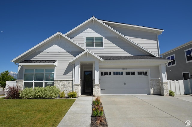 view of front facade with concrete driveway, an attached garage, stone siding, and a front yard