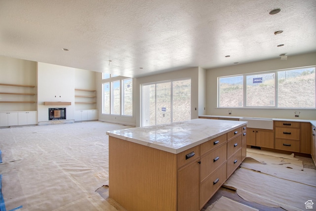 608 E 1310 S, Payson, UT 84651 - kitchen with a textured ceiling, built in shelves, a glass covered fireplace, and a center island