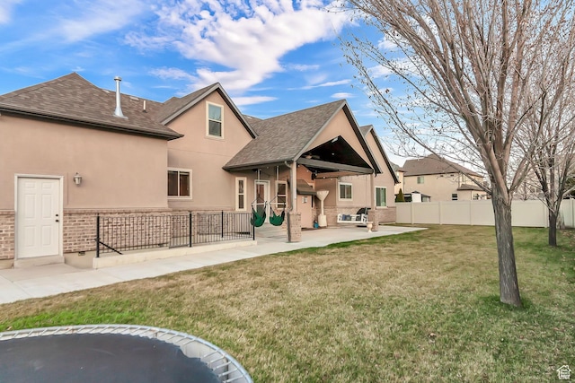 3857 S Windlass Rd W, Saratoga Springs, UT 84045 - rear view of property featuring fence, a shingled roof, stucco siding, a patio area, and a lawn