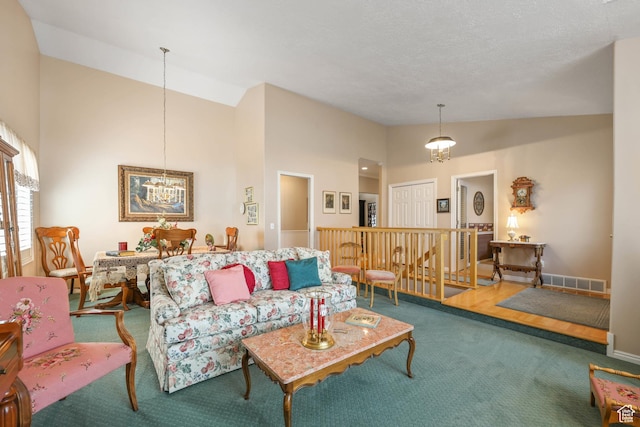 carpeted living room with a notable chandelier, baseboards, visible vents, and high vaulted ceiling
