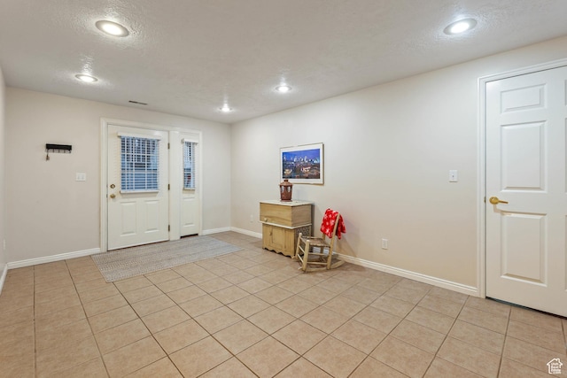 foyer featuring light tile patterned floors, baseboards, and a textured ceiling