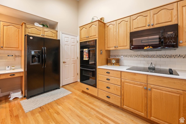 kitchen with decorative backsplash, light wood-style floors, black appliances, and light countertops
