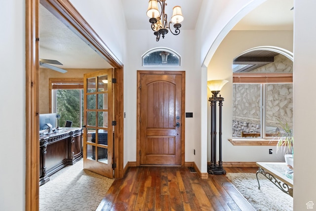 entryway featuring arched walkways, a notable chandelier, baseboards, and hardwood / wood-style flooring
