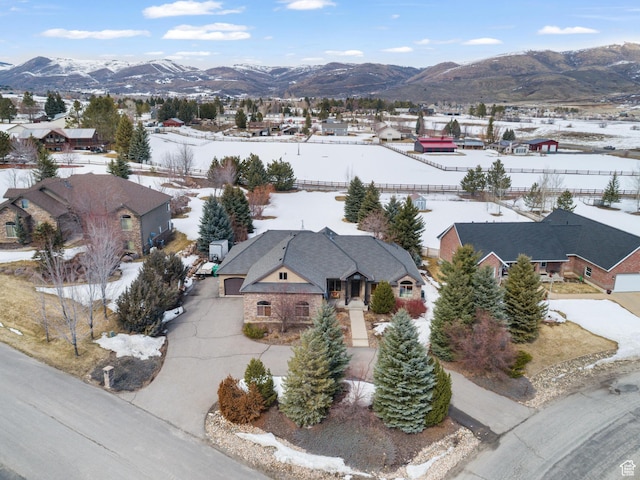 snowy aerial view featuring a mountain view and a residential view