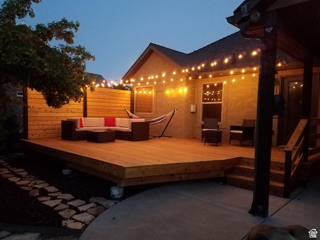 deck with an outdoor living space with a fire pit and fence