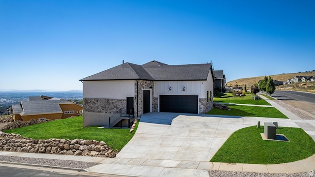 view of front facade featuring stone siding, an attached garage, concrete driveway, and a front yard