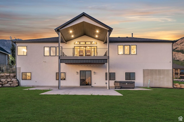 back of house with a patio, stucco siding, a lawn, and a hot tub