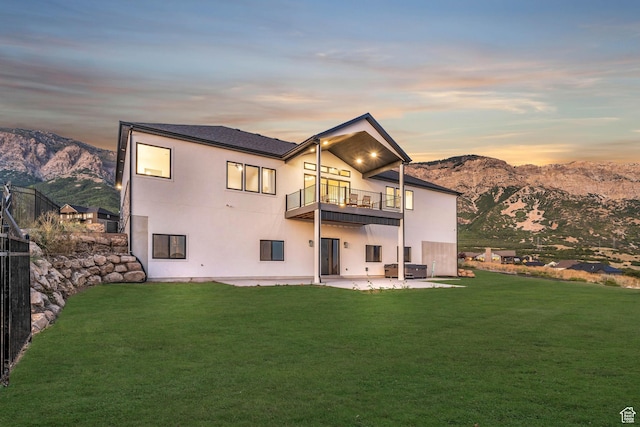 rear view of house with a yard, a balcony, a mountain view, and a patio area