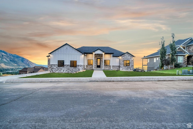 view of front of house with stone siding, a lawn, board and batten siding, and a mountain view