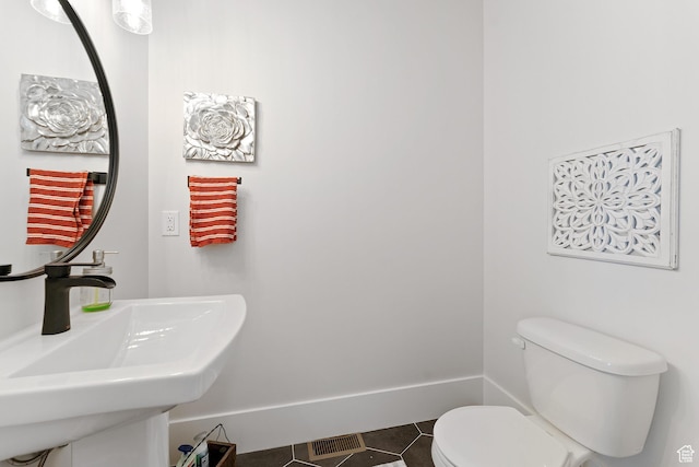 bathroom with visible vents, toilet, a sink, tile patterned flooring, and baseboards