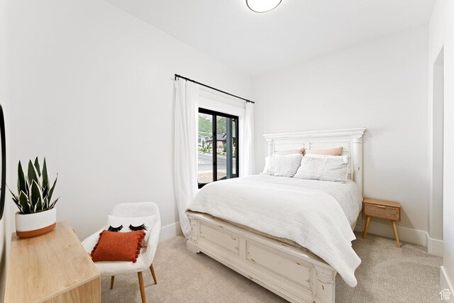 bedroom with baseboards, light carpet, and access to outside