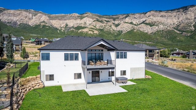 back of property featuring a patio, a balcony, fence, a yard, and a mountain view