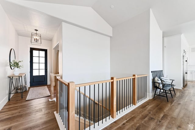 entryway with a chandelier, vaulted ceiling, baseboards, and wood finished floors