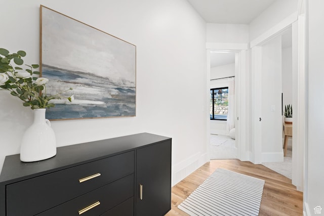 hall with light wood-style flooring and baseboards