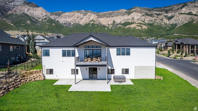 rear view of house featuring stucco siding, a lawn, fence, a mountain view, and a balcony