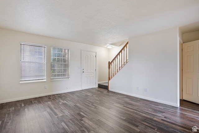 interior space with dark wood finished floors, stairway, a textured ceiling, and baseboards