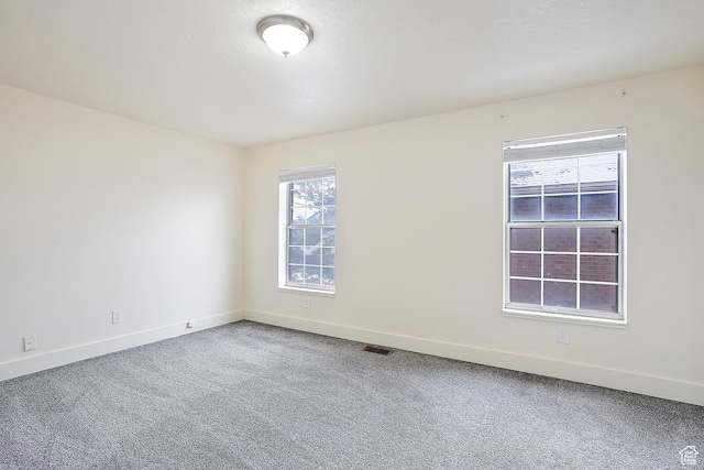 unfurnished room with baseboards, visible vents, and carpet floors