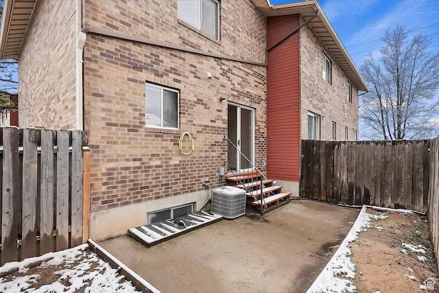 back of house featuring brick siding, cooling unit, entry steps, and fence