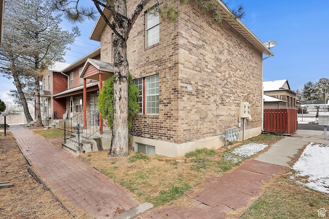 view of side of home featuring brick siding and fence