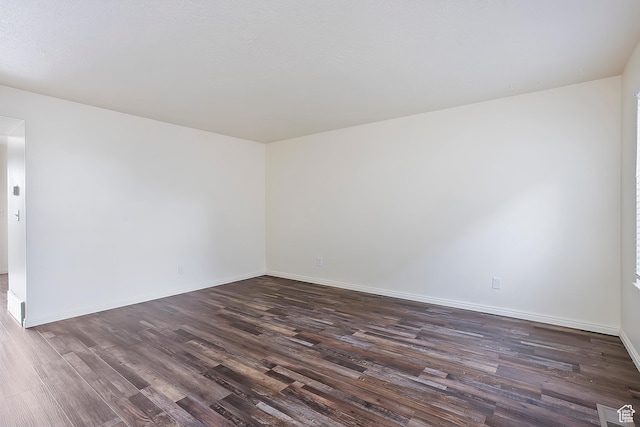 spare room featuring baseboards and dark wood-style flooring
