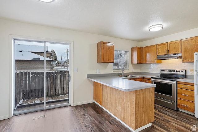 kitchen with a peninsula, dark wood-style flooring, a sink, electric stove, and under cabinet range hood