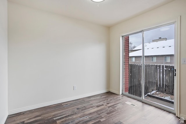 spare room with visible vents, baseboards, and wood finished floors