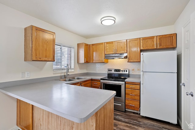 kitchen with under cabinet range hood, a sink, freestanding refrigerator, stainless steel electric range, and a peninsula