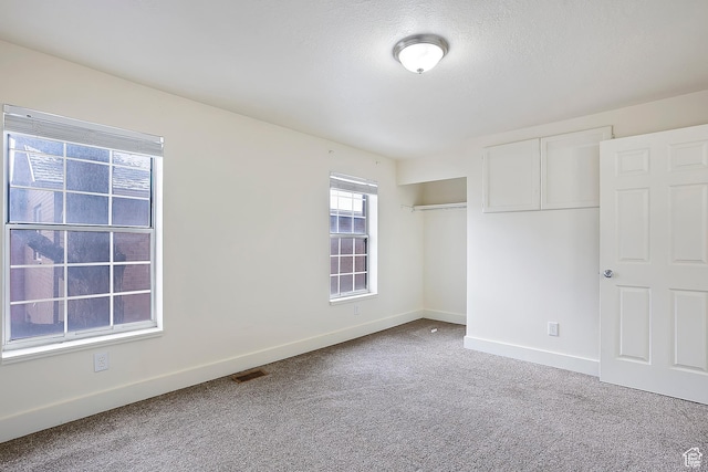unfurnished bedroom with visible vents, baseboards, carpet flooring, a closet, and a textured ceiling
