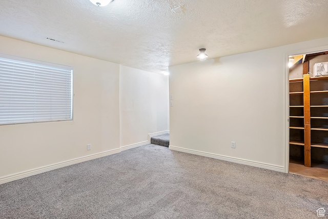 basement with visible vents, baseboards, a textured ceiling, and carpet flooring