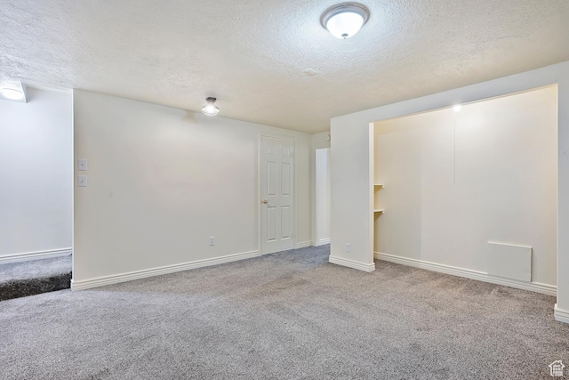 below grade area with carpet flooring, baseboards, and a textured ceiling