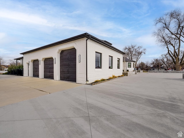 view of side of property with brick siding, driveway, and a garage