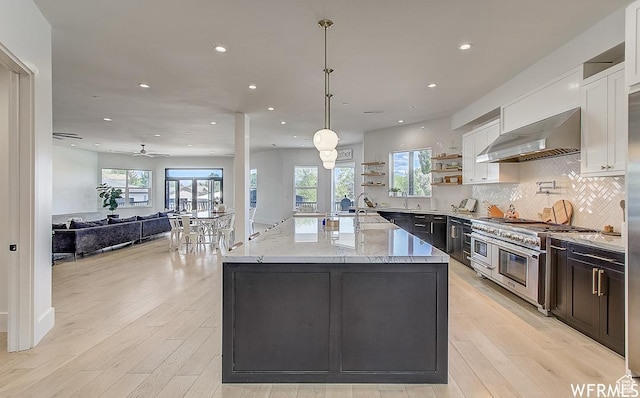 kitchen with double oven range, open shelves, backsplash, white cabinets, and wall chimney exhaust hood