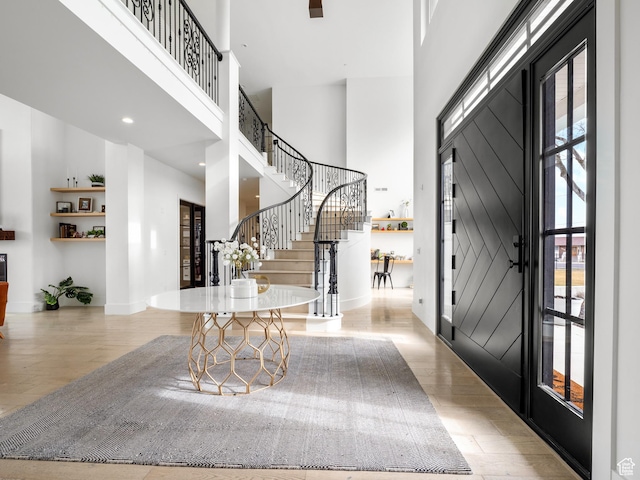 entrance foyer featuring a high ceiling, baseboards, stairs, and wood finished floors