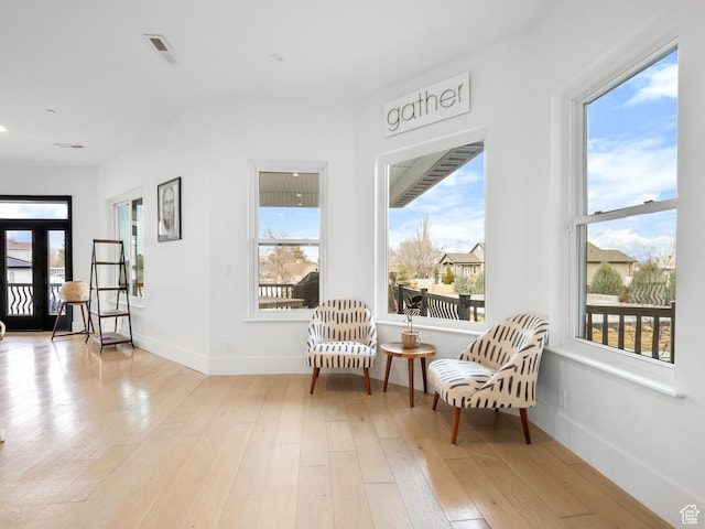 sitting room featuring baseboards, visible vents, and light wood-style floors