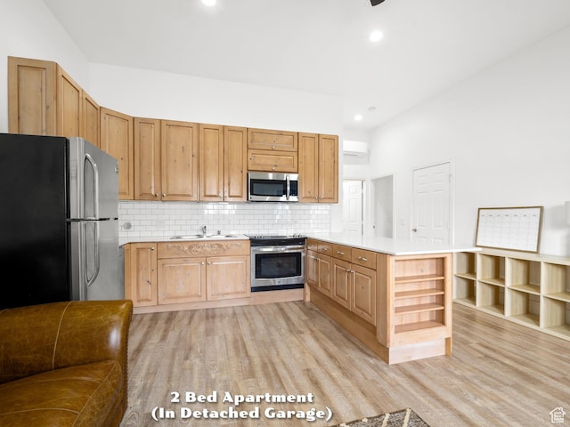 kitchen with light countertops, decorative backsplash, a sink, light wood-style floors, and appliances with stainless steel finishes
