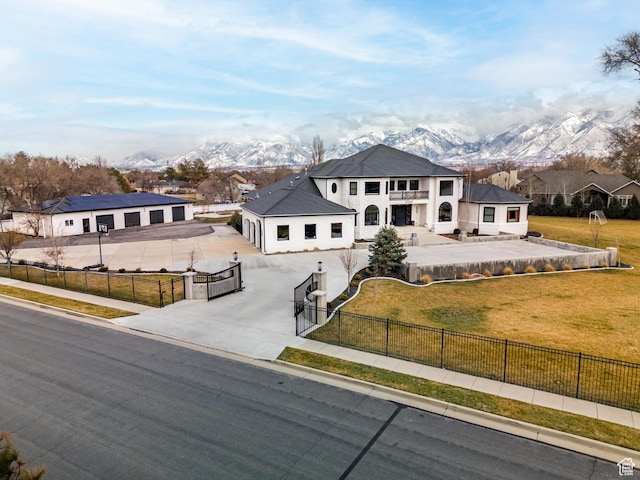 view of front of house with a fenced front yard, a front lawn, concrete driveway, and a mountain view