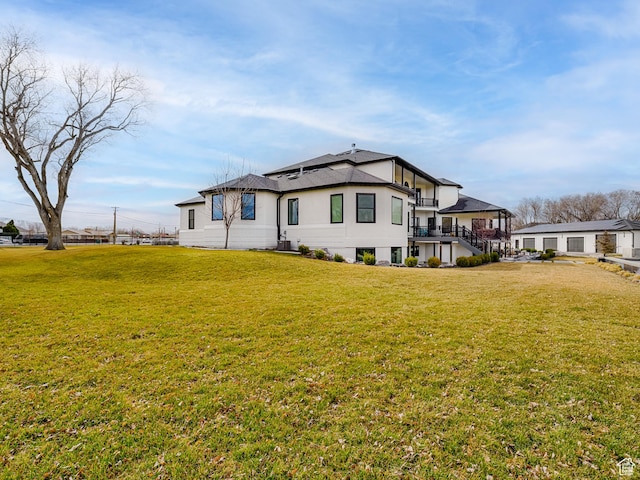 rear view of property with stairs and a lawn