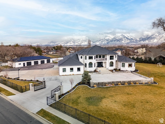 exterior space featuring concrete driveway, a fenced front yard, a mountain view, and a front lawn