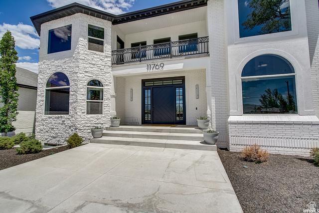 view of exterior entry featuring a balcony and brick siding