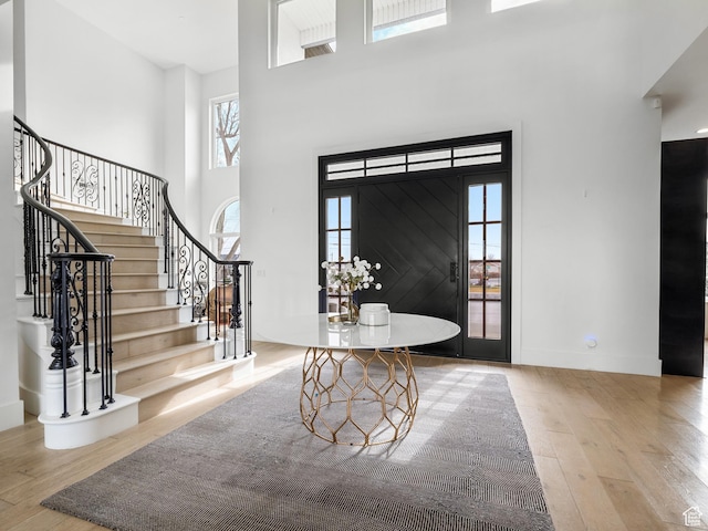 entryway featuring baseboards, wood finished floors, a towering ceiling, and stairway