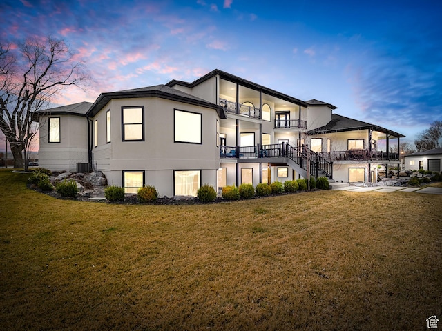 rear view of property with a balcony and a lawn