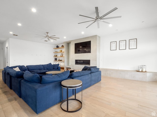 living room featuring recessed lighting, light wood-type flooring, visible vents, a high end fireplace, and a ceiling fan