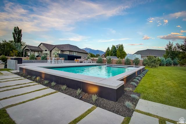 view of swimming pool featuring an infinity pool, a yard, and a patio area