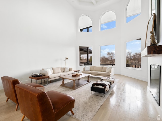 living room with baseboards, light wood-style floors, and a towering ceiling