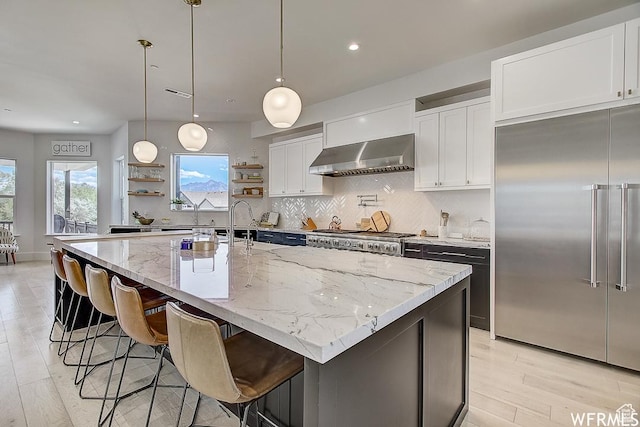 kitchen with backsplash, open shelves, stainless steel built in fridge, stove, and wall chimney range hood