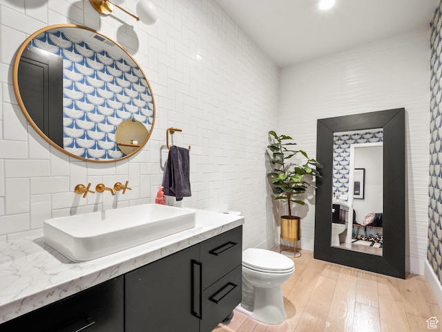 bathroom with vanity, tile walls, toilet, backsplash, and wood finished floors