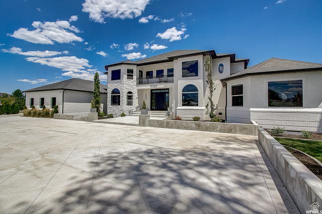 view of front of home with stone siding, a balcony, and stucco siding