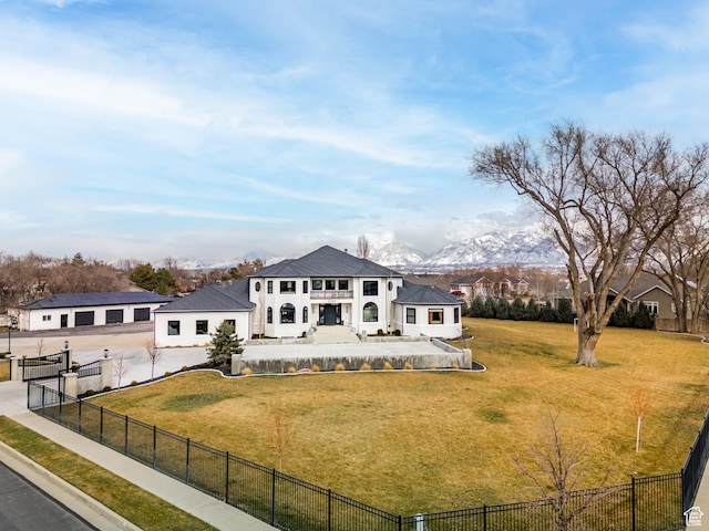 rear view of house with a fenced backyard, concrete driveway, a mountain view, and a yard